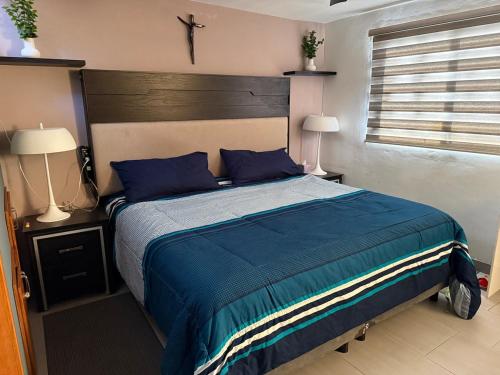 a bedroom with a bed with blue sheets and two lamps at Comfort House in Manuel F. Martínez