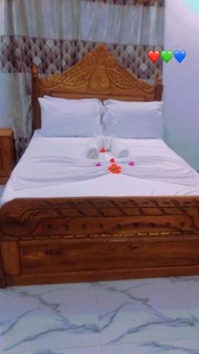a wooden bed with white sheets and decorations on it at DALENT RESiDENCE in Brusubi
