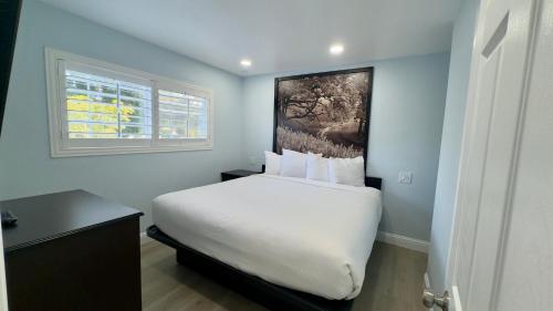 a bedroom with a white bed with a painting on the wall at Pelican Inn in Monterey
