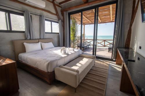 a bedroom with a bed and a balcony with the ocean at Spirit Holbox in Holbox Island