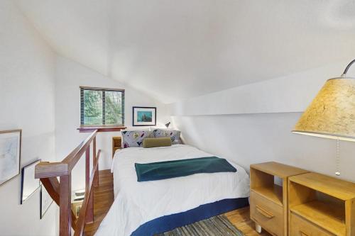 a white bedroom with a bed and a desk at Tranquil Tides Cottage in Langley