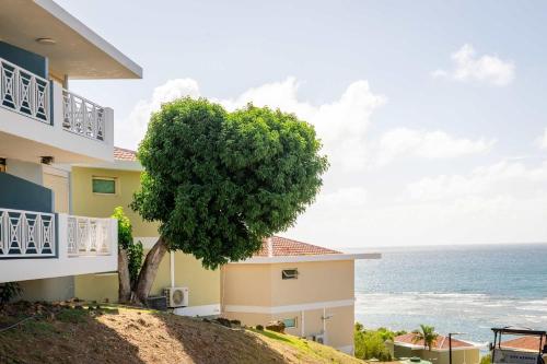 a building with a tree next to the ocean at Villa Costera 904 | Island Escapade | Culebra in Culebra