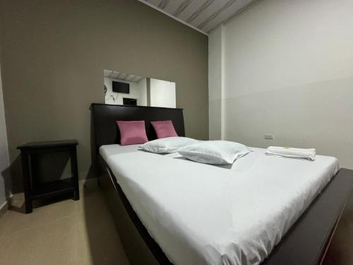 a bedroom with a large bed with pink pillows at HOSPEDAJE CASANOVA FlORIDA VALLE in Florida