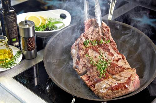 a piece of meat on a pan on a stove at Hotel Tirol Fiss 4Sterne Superior in Fiss