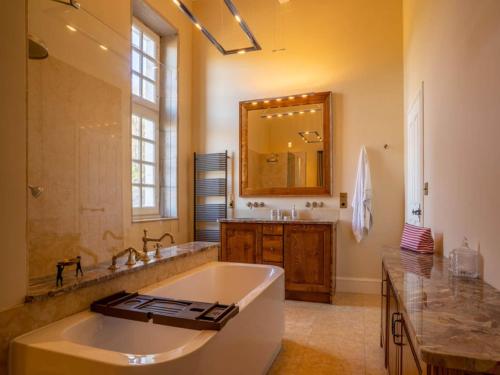 a bathroom with a large tub and a large mirror at French Villa with Pool & Games Room in Damiatte