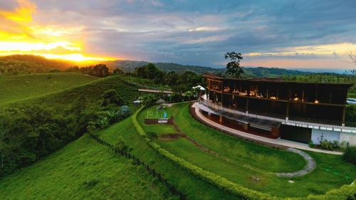 a building on a hill with the sunset in the background at Airstream Stay Private Jacuzzi & Volcano View in Monterrey