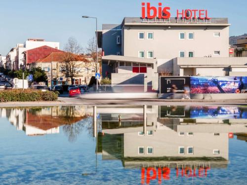 a reflection of a building in a body of water at Hotel ibis Guimaraes in Guimarães