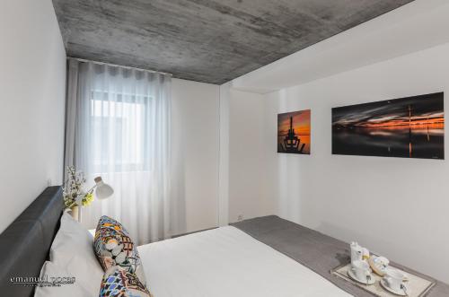 a white bedroom with a bed and a window at Innapartments - São Gonçalinho in Aveiro