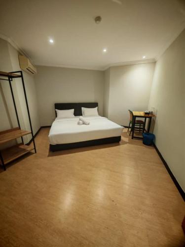 a bedroom with a white bed and a wooden floor at Swing & Pillows - Dataran Nilai in Nilai