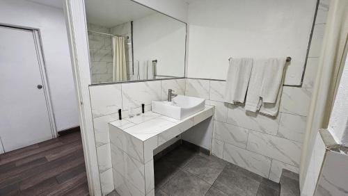 a white bathroom with a sink and a mirror at Motel Olvera in Tijuana