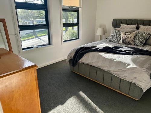 a bedroom with a bed and two windows at Modern Gem Steps from Everything You Need in Croydon North