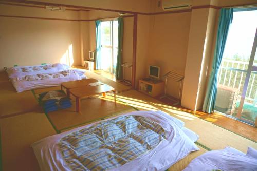a room with two beds and a table in it at 海のお宿 in Susami