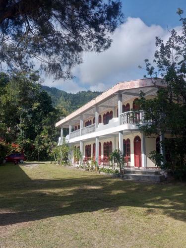 a large white building with red doors and a yard at Kings guest house in Tuktuk Siadong