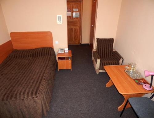 a hotel room with a bed and a chair and a table at Гостиница ИЛЕК in Aktobe