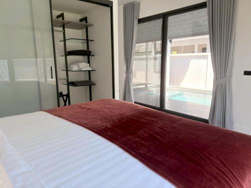 a bedroom with a bed and a large window at Akara Poolvilla Naithon Beach in Ban Sakhu