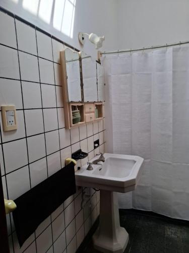 a white bathroom with a sink and a mirror at De Paso Pergamino in Pergamino