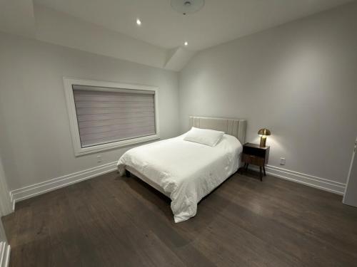 a white bedroom with a bed and a window at Modern Luxury Living in Toronto