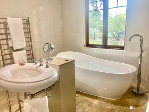 a white bathroom with a tub and a sink at The Secret Garden Burradoo in Burradoo
