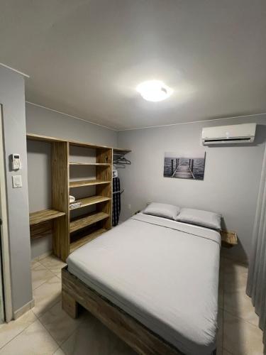 a bedroom with a large white bed and shelves at Grey-B Appartment in Dorp Sint Michiel
