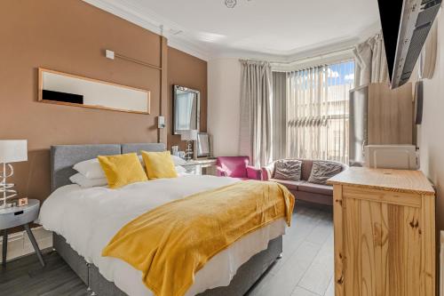 a bedroom with a large bed with a yellow blanket on it at The B & B Blackpool in Blackpool