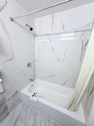 a white bath tub in a bathroom with marble walls at Economy Inn in Longview