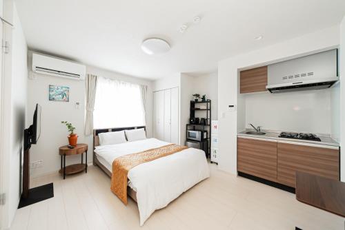 a bedroom with a large bed and a kitchen at SAIEI Hotel 东京小岩 JR京成双站直达成田羽田迪士尼适合家庭团队整栋多房型 in Tokyo
