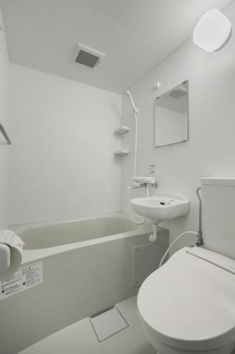 a white bathroom with a toilet and a sink at Rita Hotel Namba in Osaka