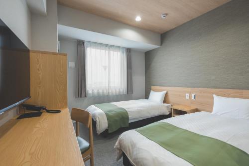a hotel room with two beds and a television at Rita Hotel Namba in Osaka