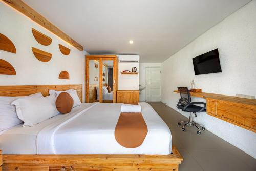 a bedroom with a bed and a desk and a television at Cove Wong Village in Tumbak Bayuh