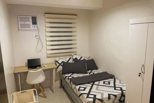 a bedroom with two beds and a desk with a laptop at Tropical Themed 2 Bedroom Condo in Mandaue City