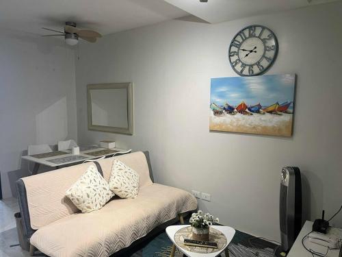 a living room with a couch and a clock on the wall at Tropical Themed 2 Bedroom Condo in Mandaue City