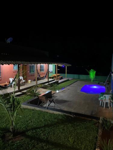 a backyard at night with a swimming pool and chairs at Casa vista da serra in Santana do Riacho