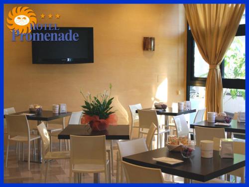 a restaurant with tables and chairs and a television on the wall at Hotel Promenade in Porto SantʼElpidio