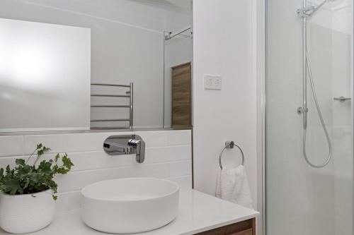 a white bathroom with a sink and a shower at 180 Degrees - Amazing Bay Views in St Helens