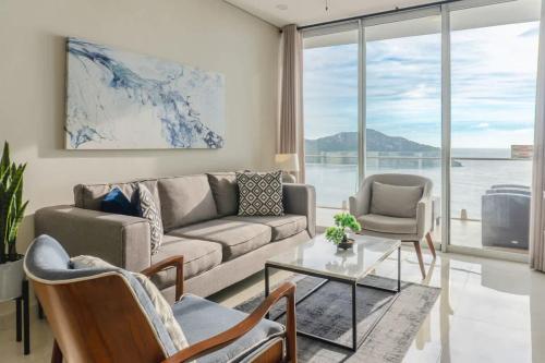 a living room with a couch and chairs and a table at Luxe Oceanfront Condo in Golden Zone in Mazatlán