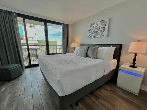 a bedroom with a large bed and a balcony at Captivating Coastal Charm - Oceanview Suite! PG 504 in Myrtle Beach