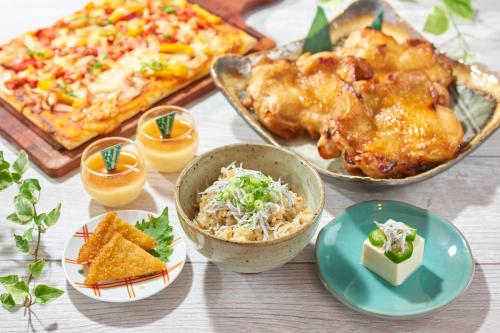 a table topped with dishes of food and a pizza at Hiroshima Tokyu REI Hotel in Hiroshima