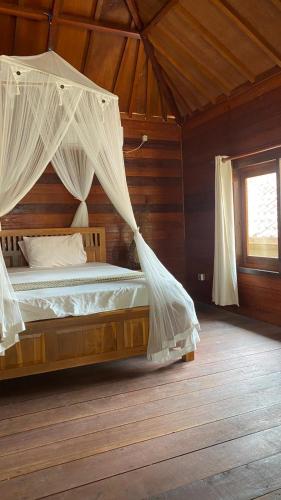 a bedroom with a bed with mosquito net at Biru Meno Beach Bungalows in Gili Meno