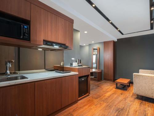 a kitchen with wooden cabinets and a counter top at Mercure Jakarta Grogol in Jakarta