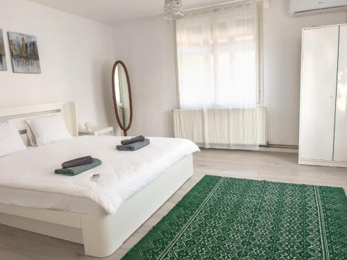 a white bedroom with a white bed and a green rug at Ethno House Andrej in Korbovo