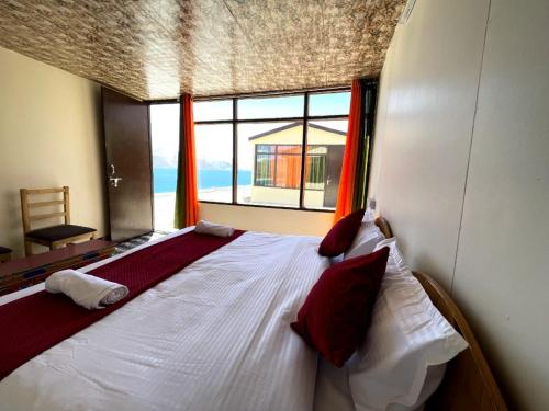 a large bed in a room with a large window at zoz camp pangong lake in Lukung