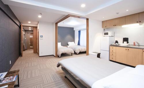 a hotel room with two beds and a kitchen at Shinka Hotel Susukino in Sapporo