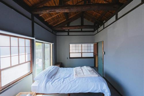 a bedroom with a bed and two windows at oribe guesthouse in Tajimi
