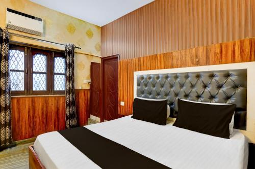a bedroom with a large bed with a leather headboard at Super Hotel O Dehradun City Centre Formerly Downtown in Dehradun