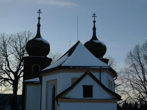a church with two domes with snow on the roof at Chalupa Na Bucharu in Javorná