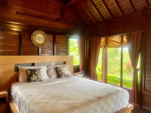 a bedroom with a large bed and a large window at Pondok Kayu Pathavi in Baturiti