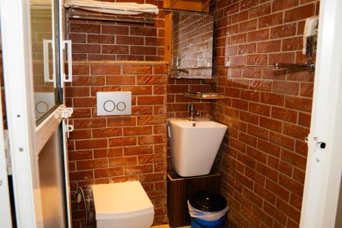 a brick walled bathroom with a toilet and a sink at Lamatar Hills Resort in Pātan