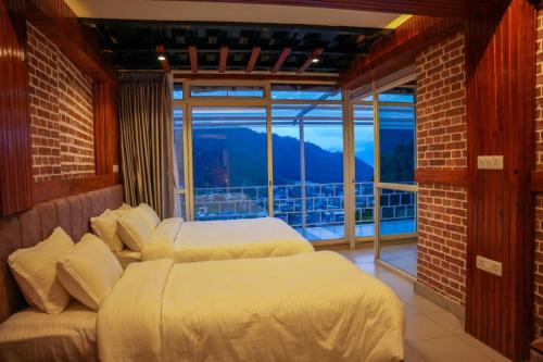 two beds in a room with a balcony at Lamatar Hills Resort in Pātan