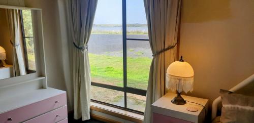 a bedroom with a window with a view of a field at Riverview Coastal Retreat Sleeps 6 Walk to Beach Great Ocean Road in Peterborough