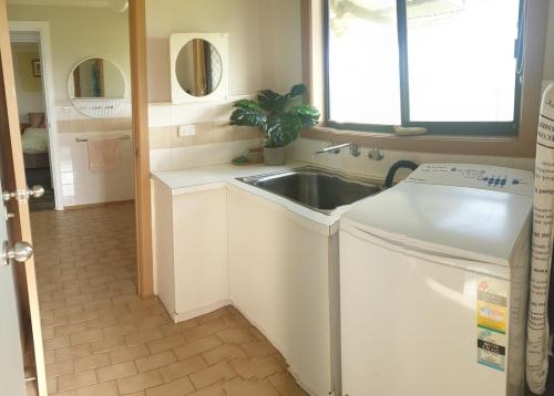 a bathroom with a washing machine and a sink at Riverview Coastal Retreat Sleeps 6 Walk to Beach Great Ocean Road in Peterborough